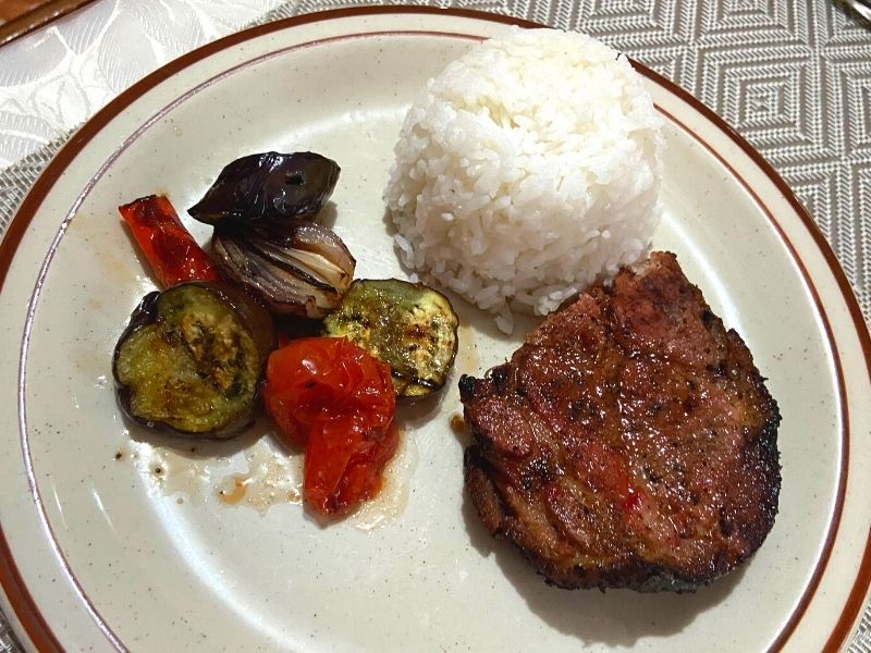 smoked pork shoulder on a plate with rice and grilled vegetables