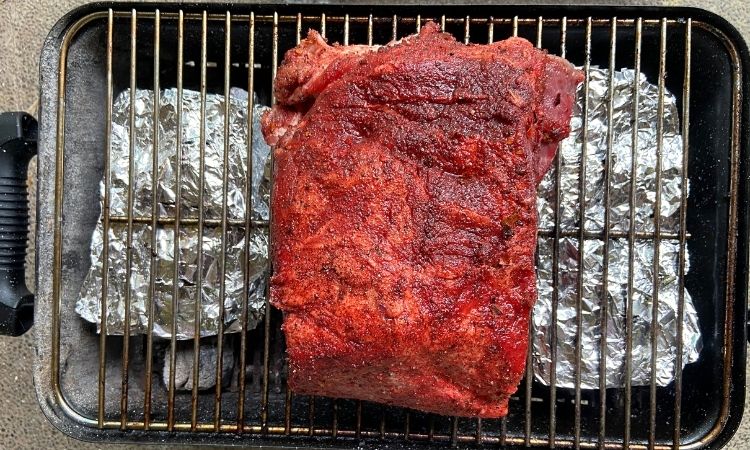 smoking pork shoulder in a charcoal grill